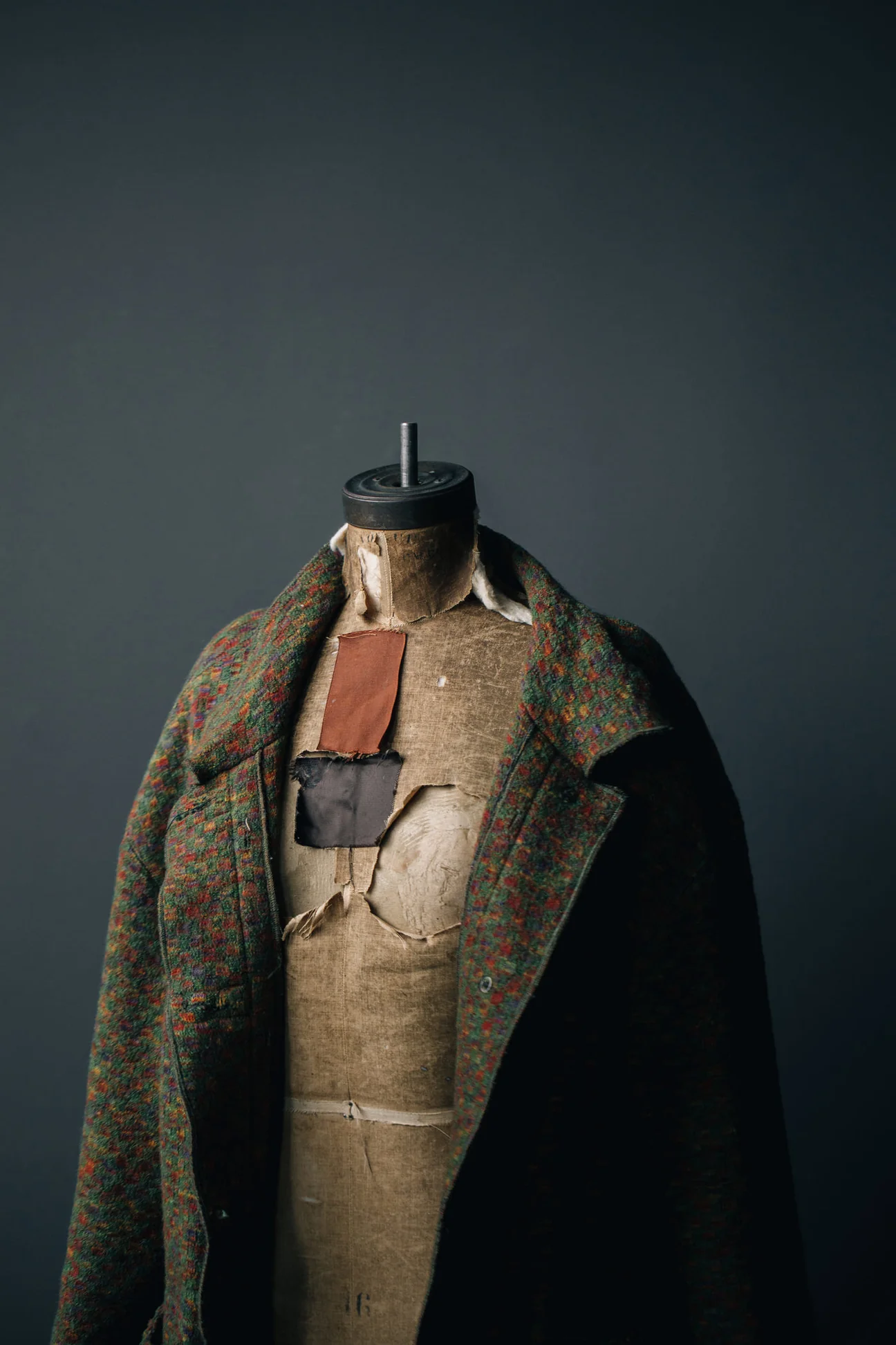A long moss tweed coat on a tailor’s form