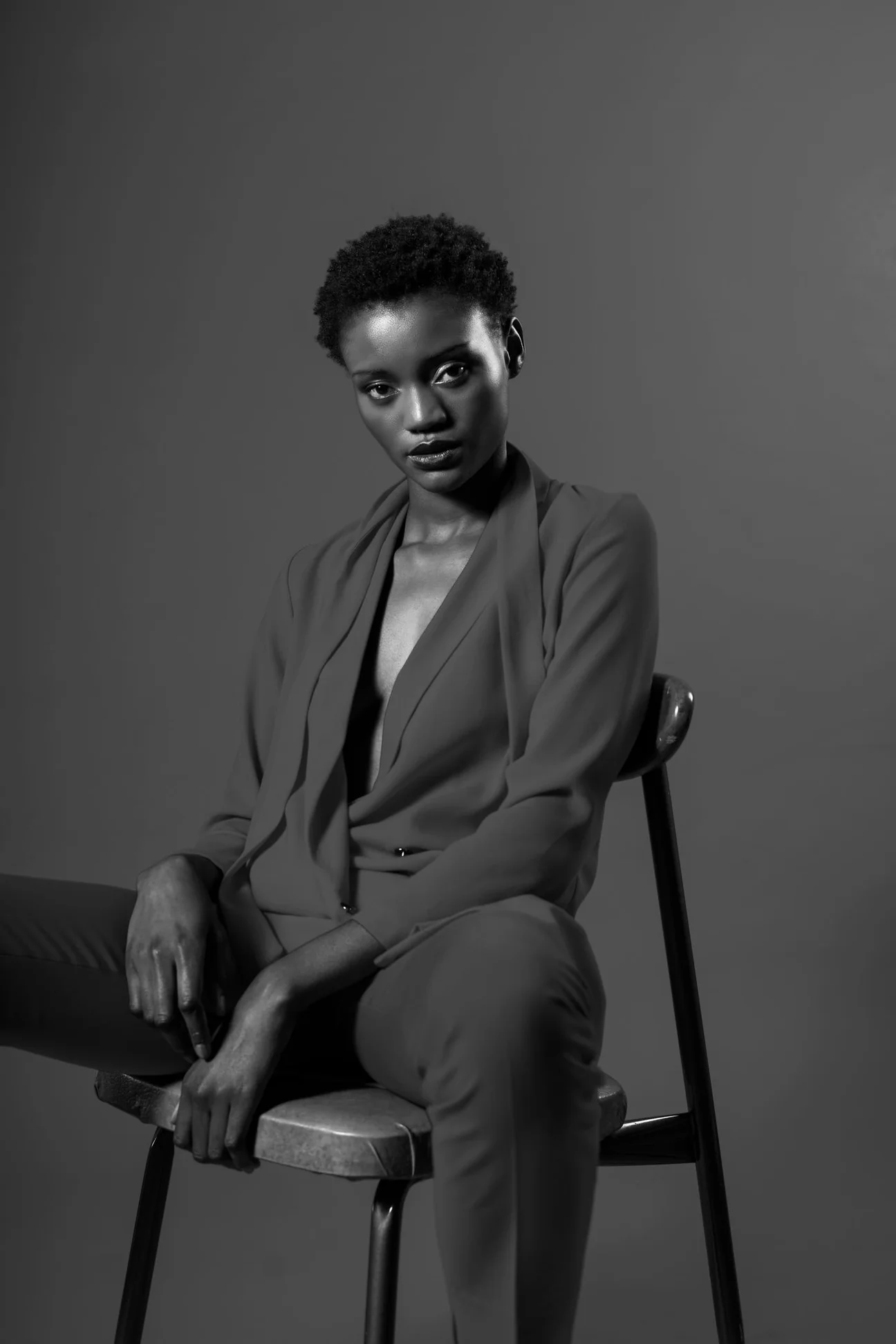 Woman seated in a black tailored jacket and trousers