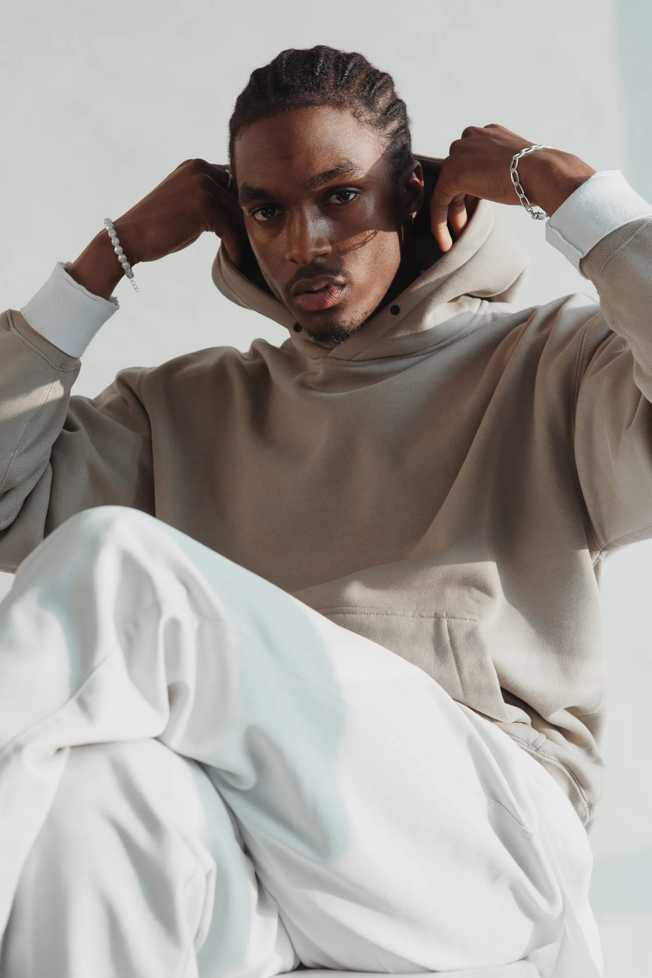 Man in a putty loopback cotton hoodie and ecru trousers