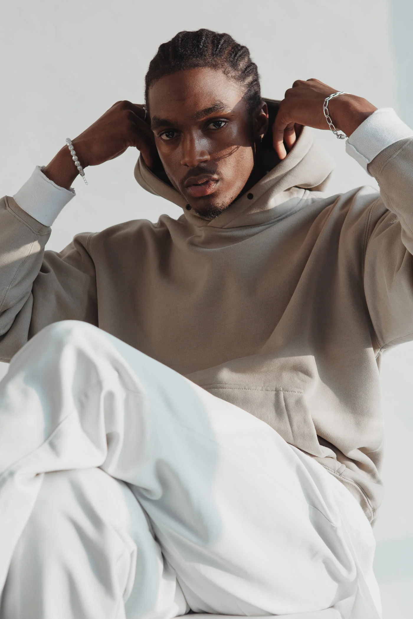 Man in a putty loopback cotton hoodie and ecru trousers
