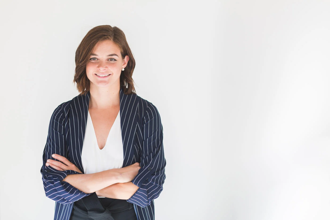 Woman in a navy pinstripe blazer over a white top, arms folded